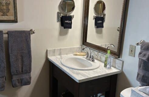 Greylock bath is newly renovated with stone counter over a new vanity, large mirror, and new porcelain flooring.