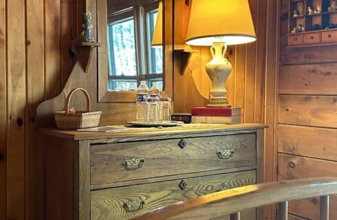 The Monument Room dresser with a lamp, accessories, and basket of amenities.