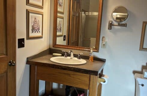 The newly renovated Shared bath has a new vanity with a solid wood counter, large mirror and a rustic porcelain floor.