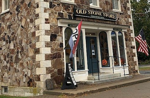 Facade of a storefront with arched windows, sign and hanging flags, inside an old stone building