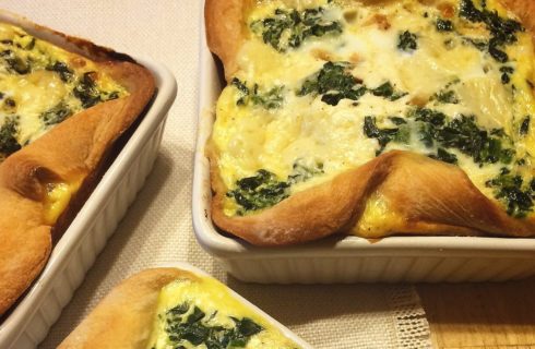 Three egg and spinach breakfast quiches in white dishes on a cream placemat